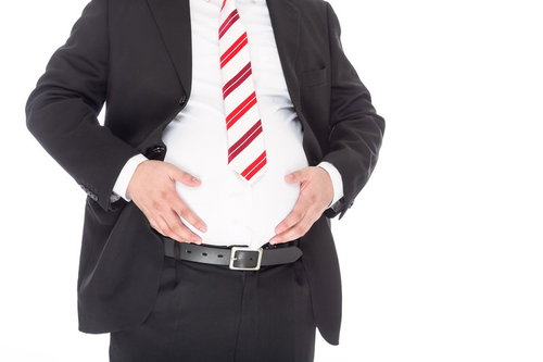 腹回りを気にするスーツ姿のサラリーマン男性