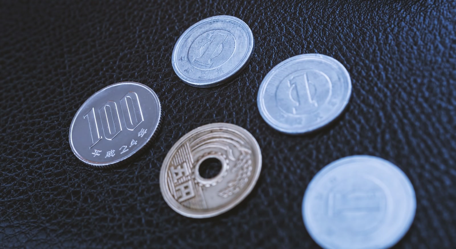 紺色の生地に散らばった100円硬貨と1円硬貨の複数枚