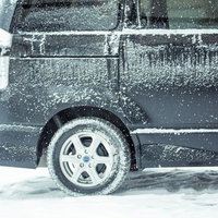 吹雪の駐車場で雪まみれの黒いワゴン車の写真