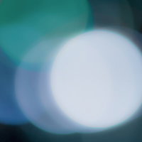 暗い場所に浮かぶ白や青のぼやけた丸い光のボケ写真の写真