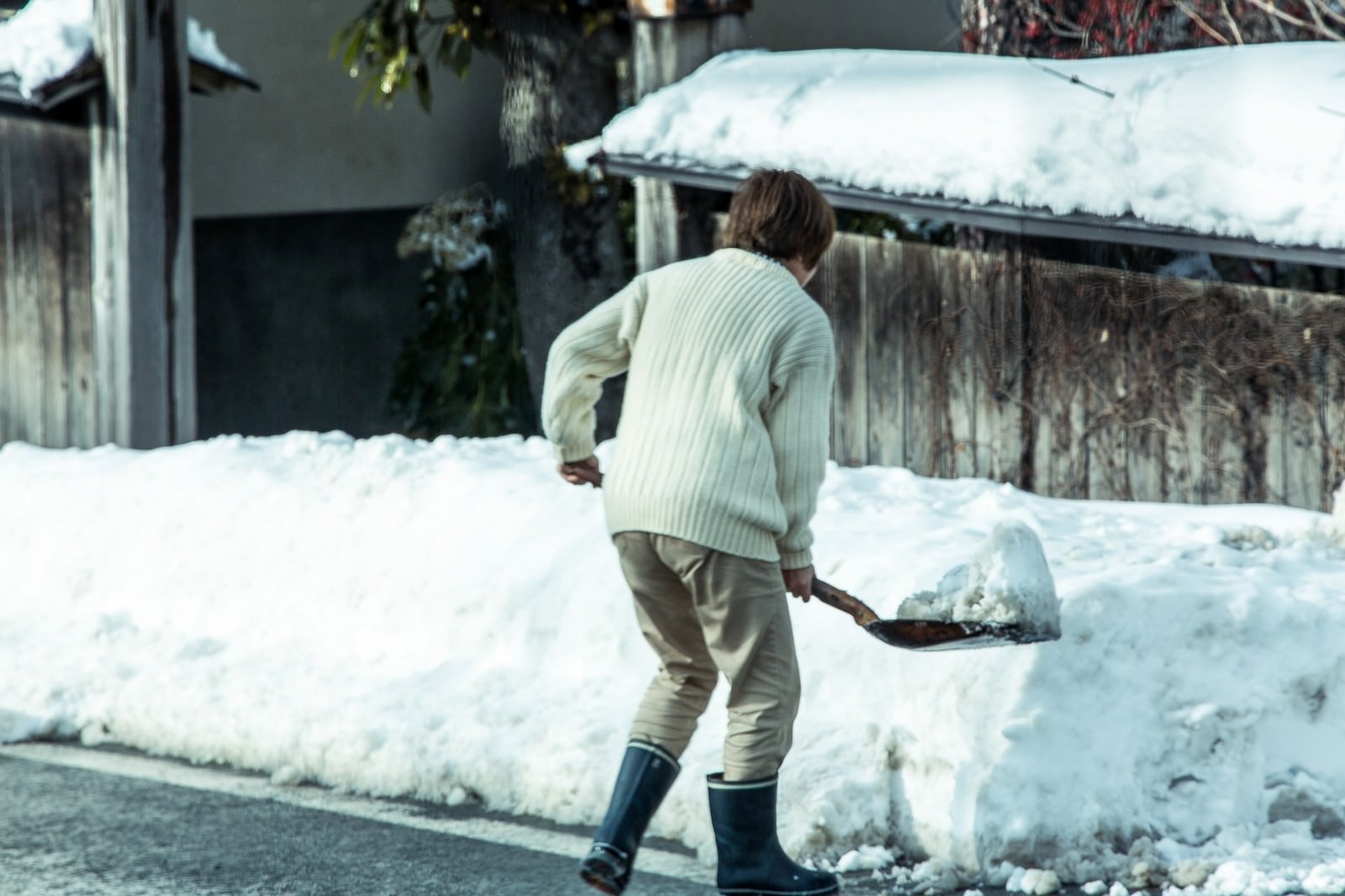 雪が積もった屋外でシャベルを使って雪かきする人