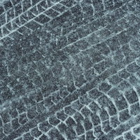 暗い地面に白いタイヤ跡が残る雪のアスファルトのテクスチャーの写真