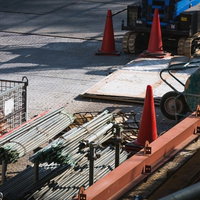 三角コーンと建設機械が並ぶ工事現場の資材置き場の写真