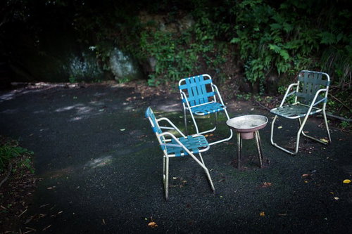 アスファルトの上の折りたたみ椅子と丸テーブルの朽ちた休憩場所