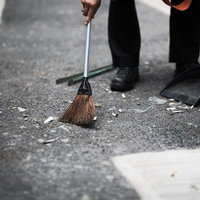 道路をほうきとちりとりで清掃する人の写真