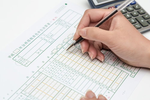 申告書類に記入する手元と電卓