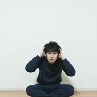 ワンルームで頭を抱える無職の男性。今後の不安と葛藤の写真