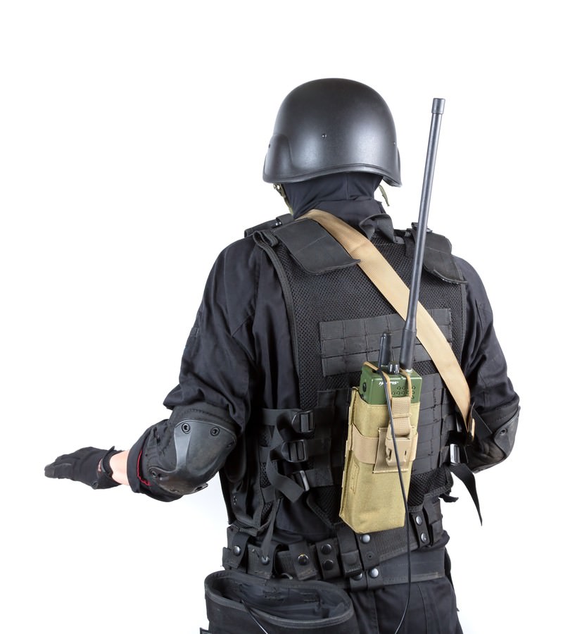 戦術装備の人物が後ろ向きにハンドサインを出す［モデル：モデルリリース］