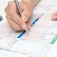 電卓を横に確定申告書にペンで記入する手元の写真