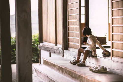 レンガ壁の建物の段差に腰かける子供の後ろ姿