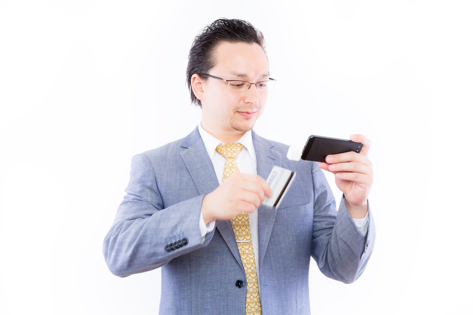 スマホとカードを両手で持つグレースーツの眼鏡の男性［モデル：Max_Ezaki］