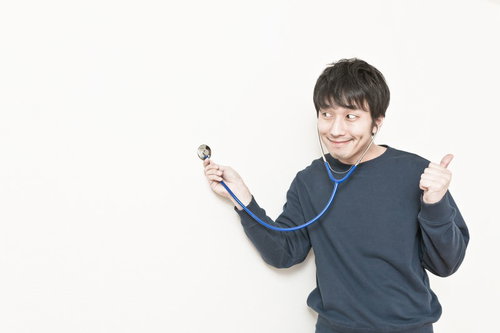 聴診器を胸に当てるトレーナー姿の男性