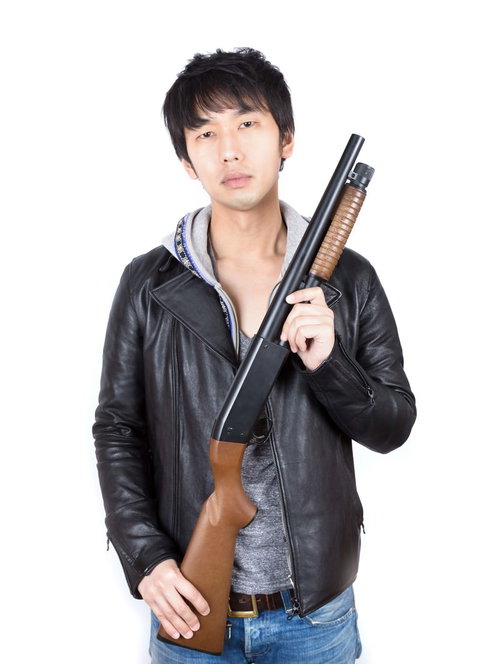 白背景でショットガンを肩に担ぐ革ジャンの男性