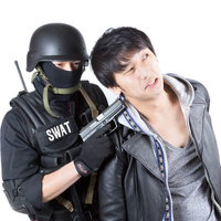 SWAT装備の隊員に拘束されるグレーの服の男性の写真