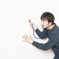 聴診器を両手で持つグレーシャツの男性の写真