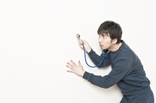 聴診器を両手で持つグレーシャツの男性