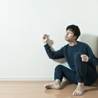 恐る恐る隣の様子を壁ドンする男性の写真