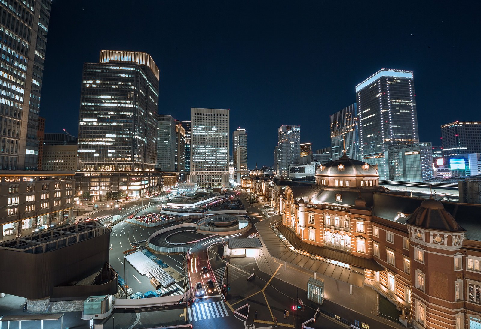 高層ビルとレンガ色の歴史的建物が並ぶ東京駅と丸の内の夜景