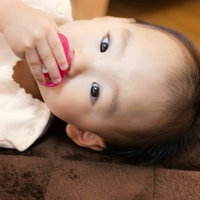 おしゃぶりを触る赤ちゃんの顔アップの写真
