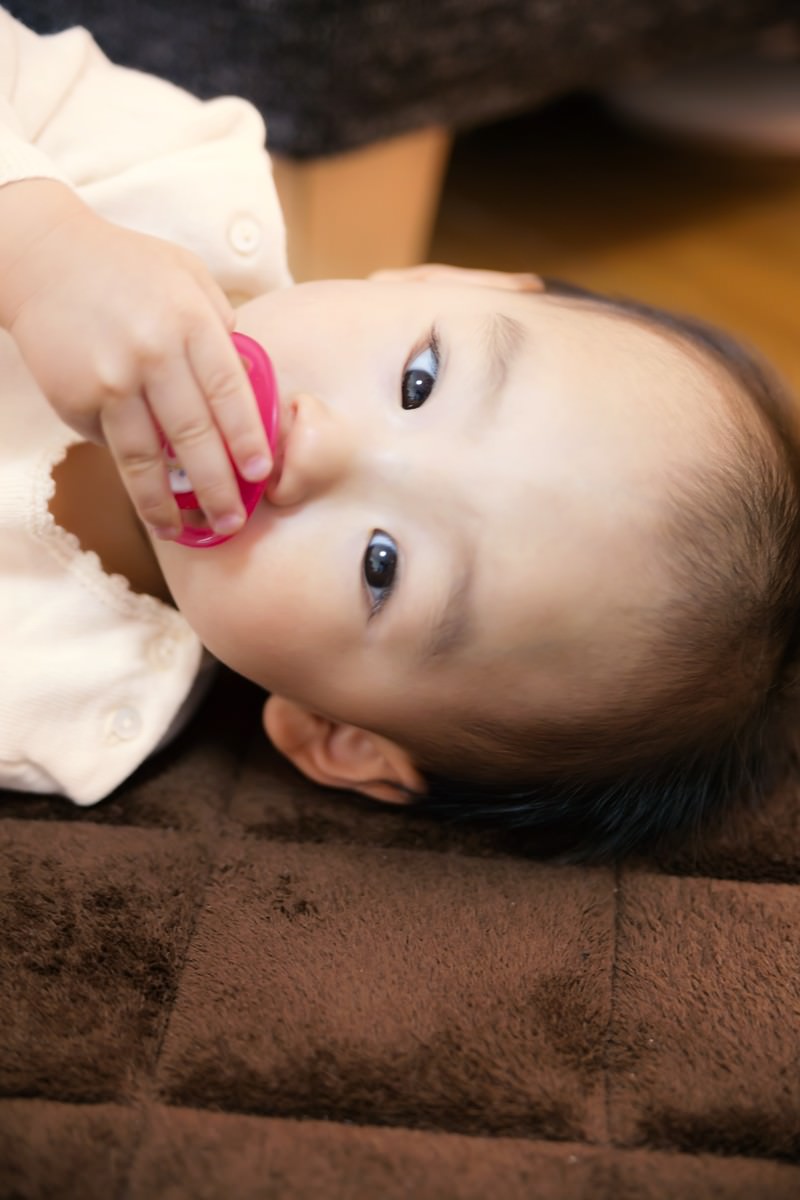 横たわりおしゃぶりを持つ赤ちゃん［モデル：あんじゅ］