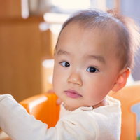 白い服を着たつかまり立ちの赤ちゃんの写真