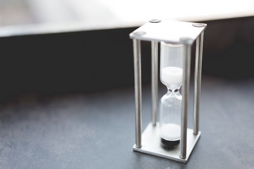 テーブルに置かれた白い砂時計のビジネス時間管理