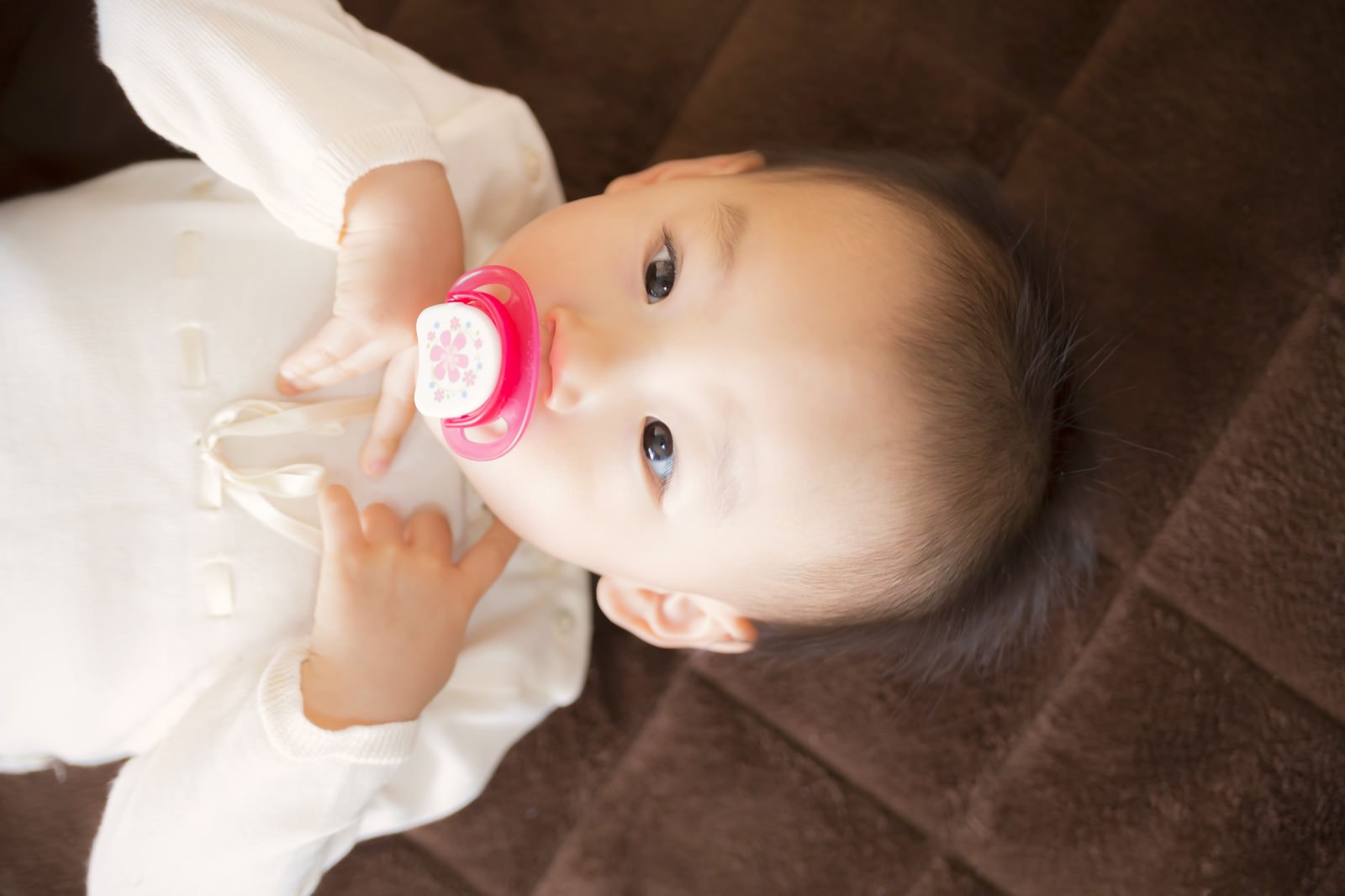 おしゃぶりを咥えて哺乳瓶を持つ赤ちゃん［モデル：あんじゅ］