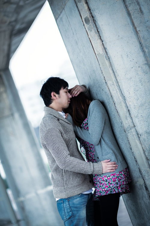 コンクリート壁の前でくっつくカップル
