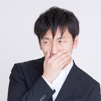 年収低すぎて口に手をあてるビジネスマンの写真