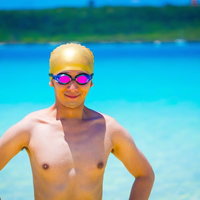 プールの前で黄色い水泳帽とピンクのゴーグルを付けて立つ男性の写真