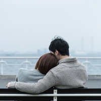 ベンチで肩を寄せ合う恋人の写真