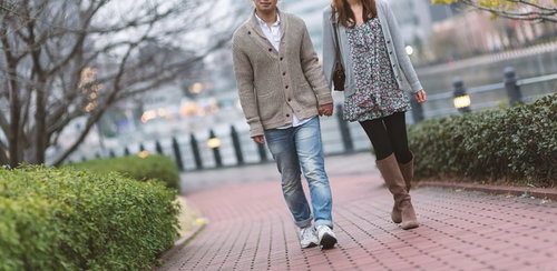 歩道を手をつないで歩くカップル
