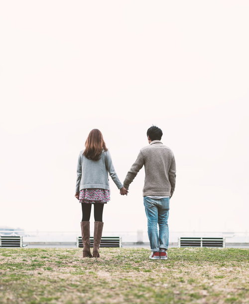 公園で手をつなぐカップルの後ろ姿