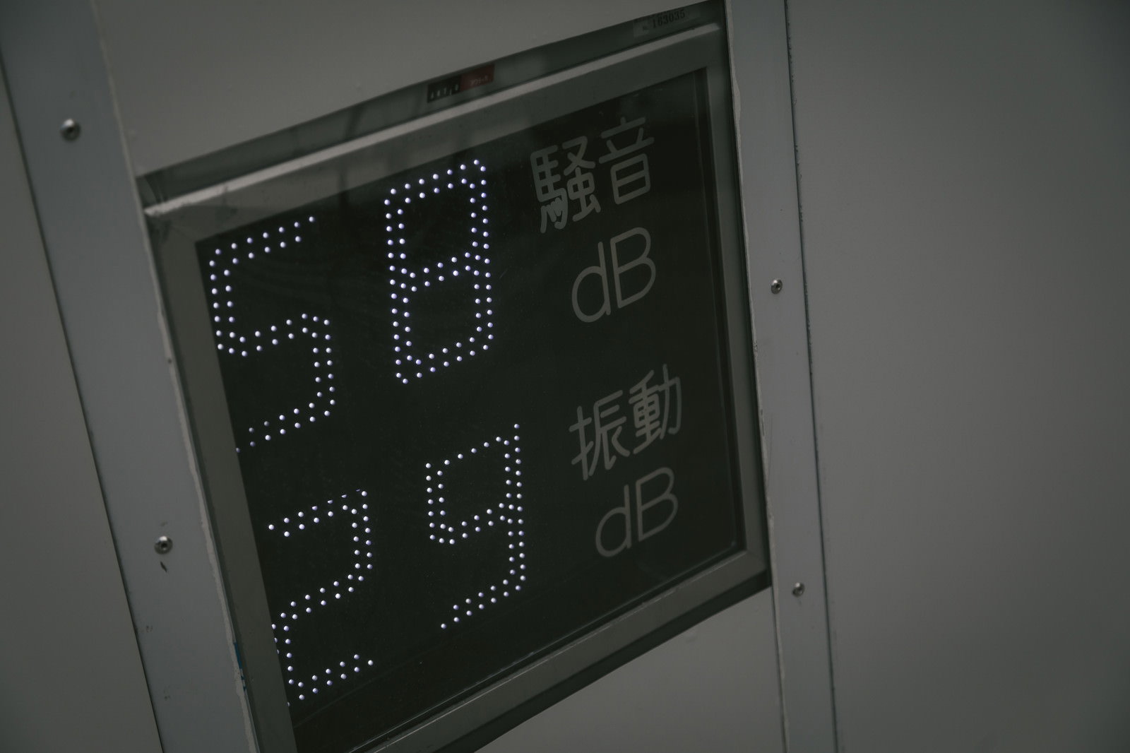 緑色のデジタル数値で騒音レベルを表示する工事現場のパネル