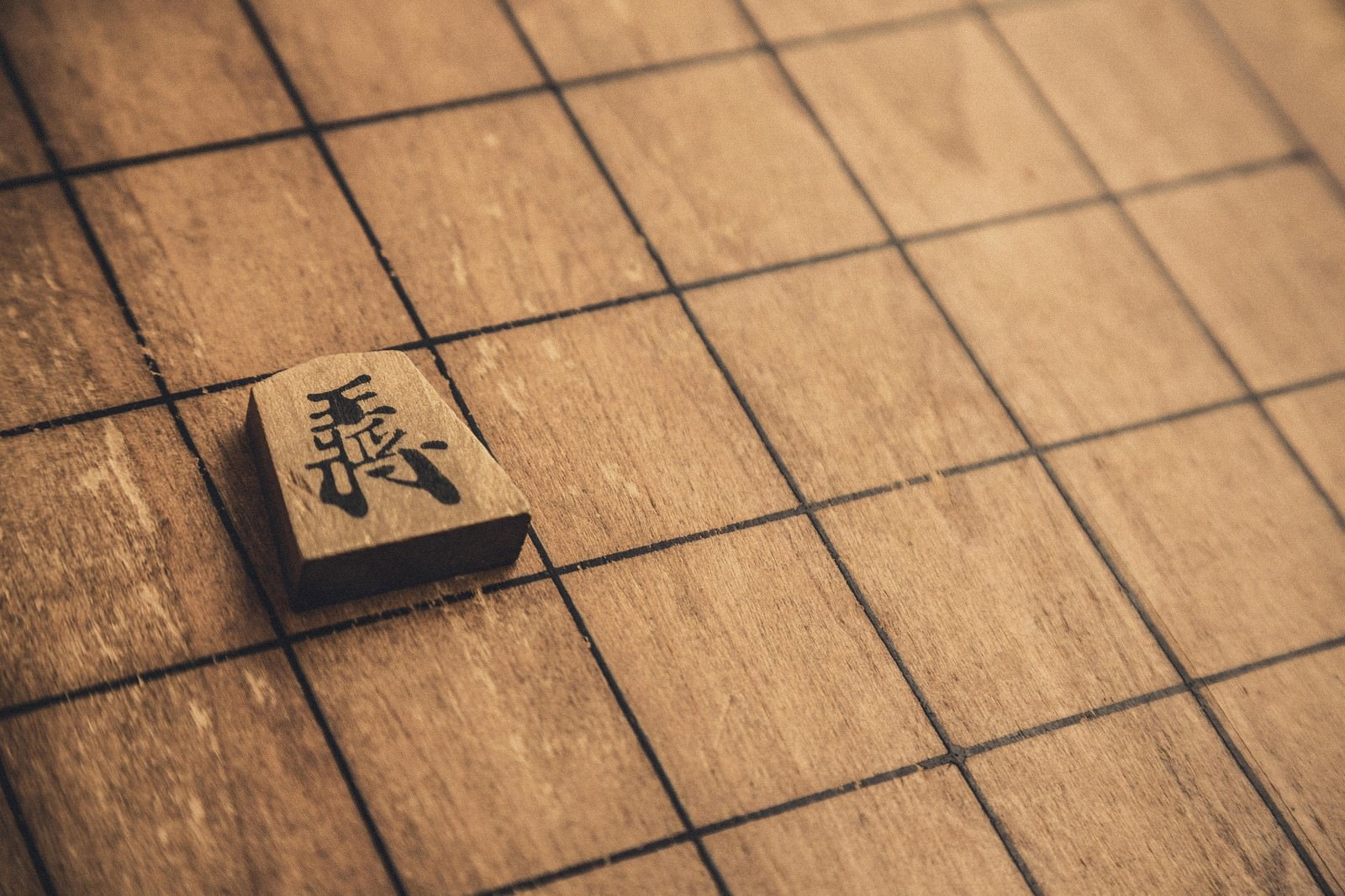 木製の将棋盤の上に置かれた王将の駒