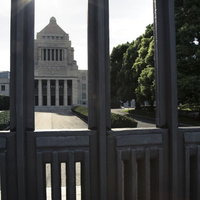 閉門の柱越しに見える国会議事堂と樹木の写真