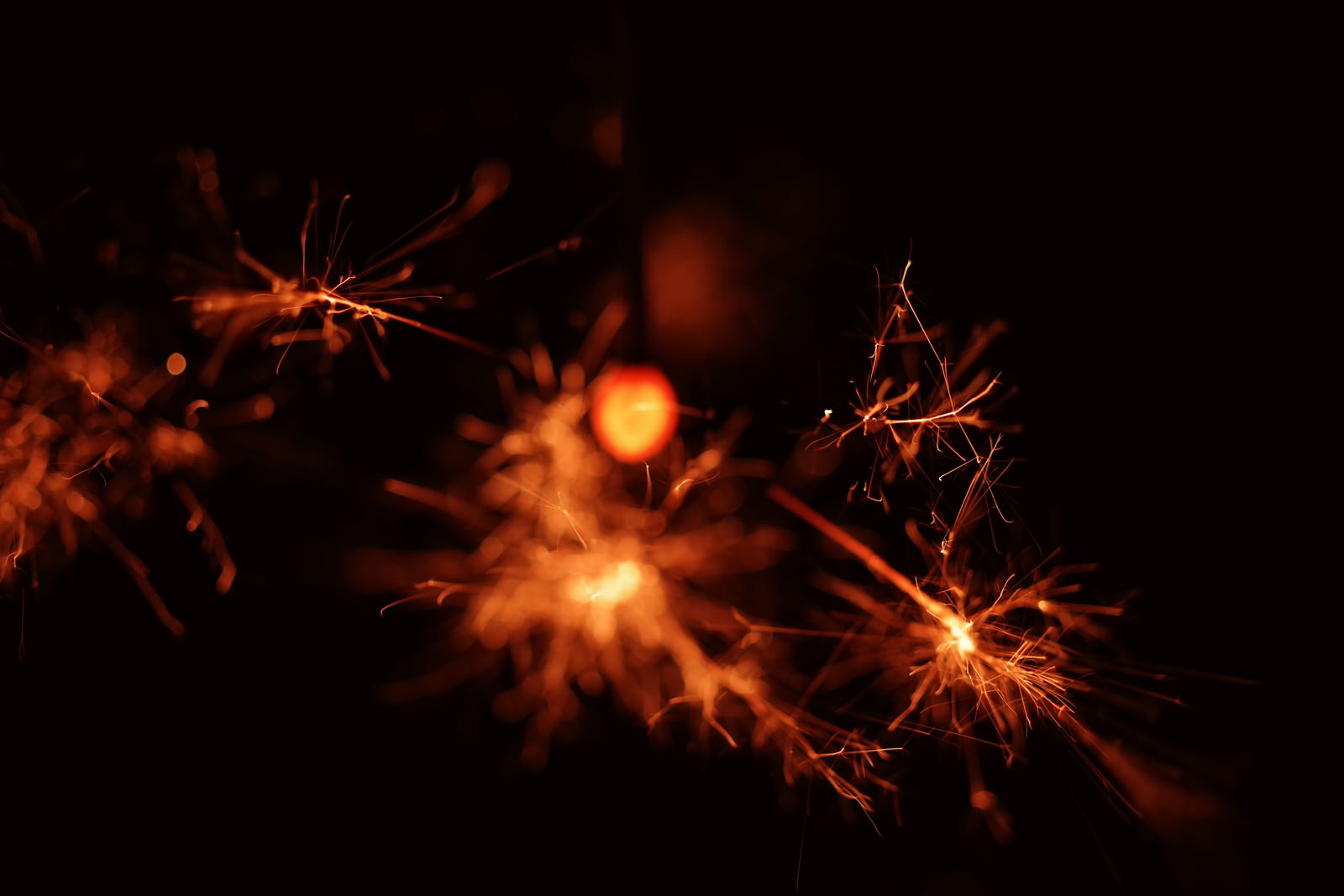 暗闇の中でオレンジ色の火花を散らす線香花火