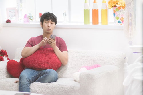 彼女の部屋でソファーに座ってスマホをチェックする男性