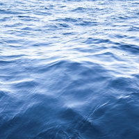 静かな沖の波が重なる海面の写真