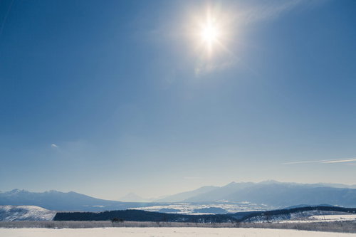雪が積もった山々を望む冬の雪山風景、澄んだ青空と針葉樹林