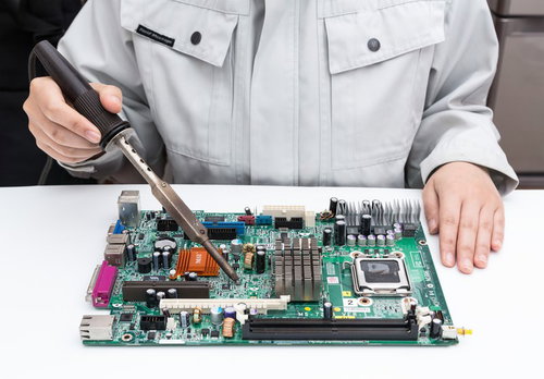 半田ゴテでプリント基板を修理する作業員の電子部品はんだ付け作業