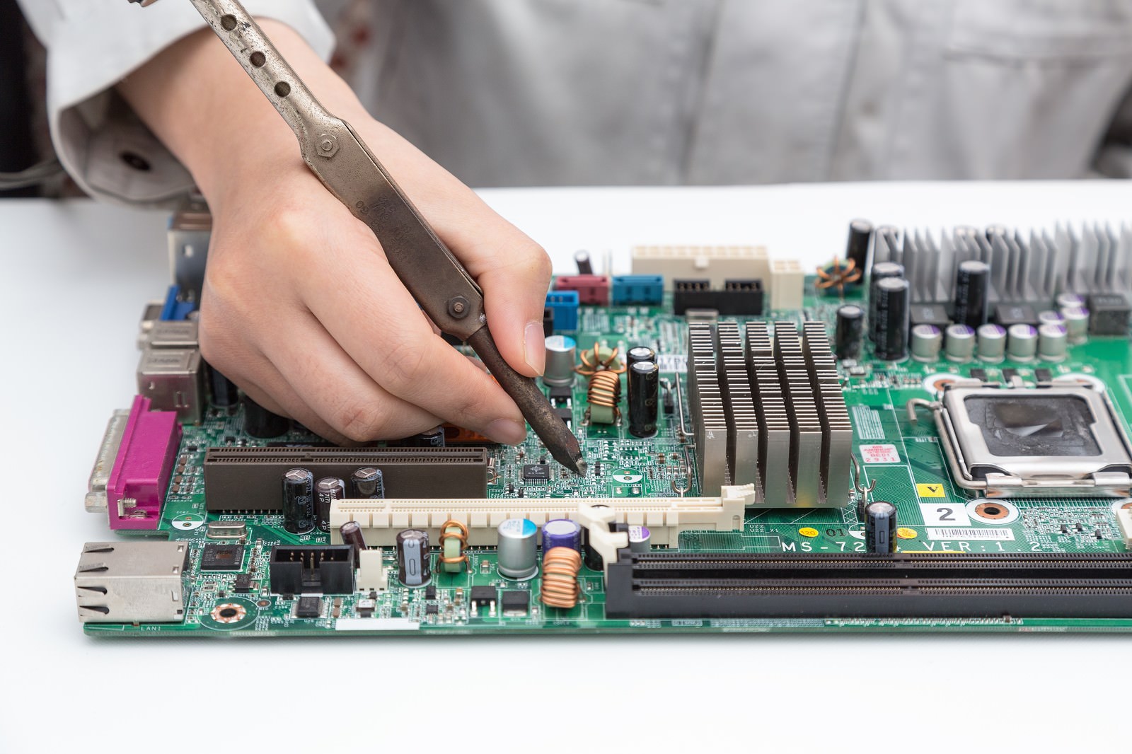 高温の半田ゴテを素手で持ってマザーボードの基板を修理する作業員