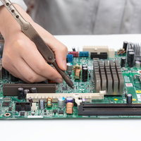 高温部分を持って基板を修理する作業員の写真