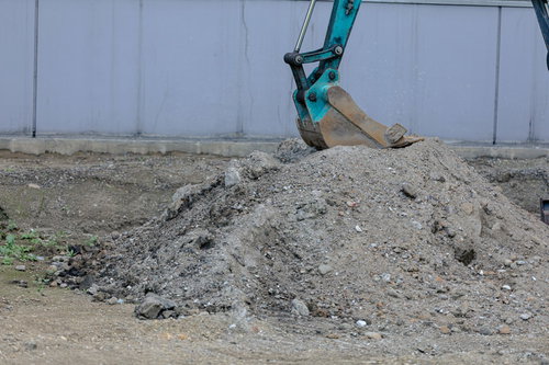 工事現場で土を掘削する黄色いショベルカーの重機作業