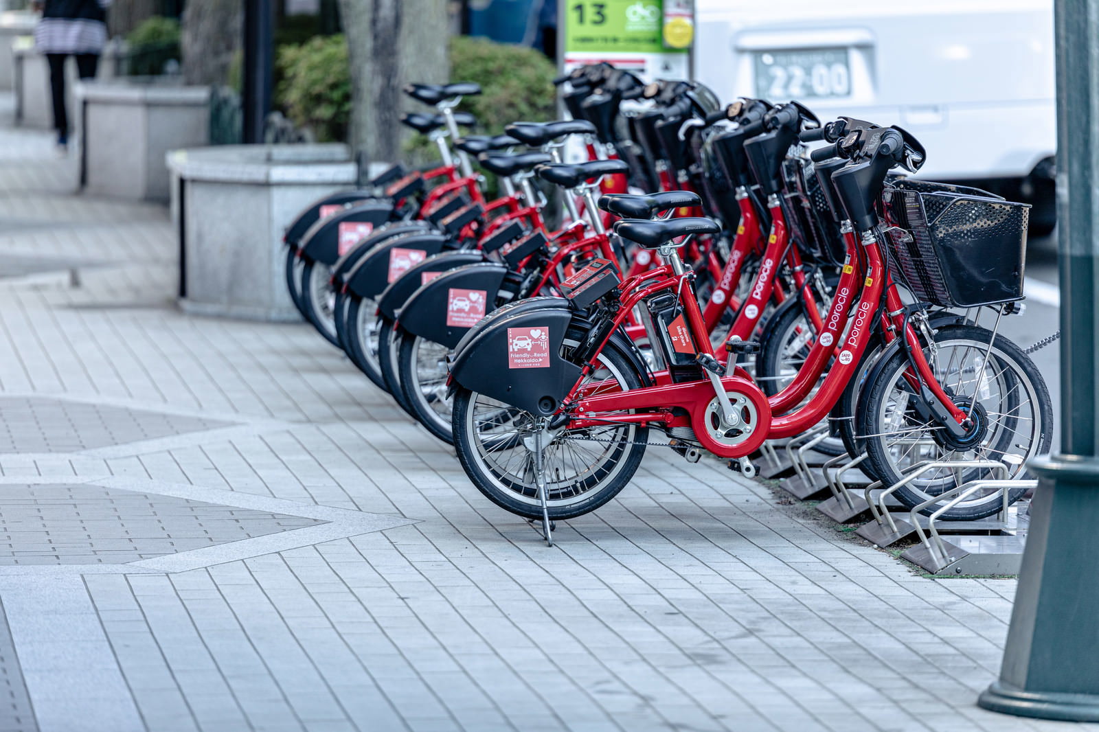 駐輪場に整然と並ぶ赤いフレームのレンタサイクル