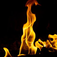 黒い背景に立ち上がる鮮やかなオレンジ色の炎の写真