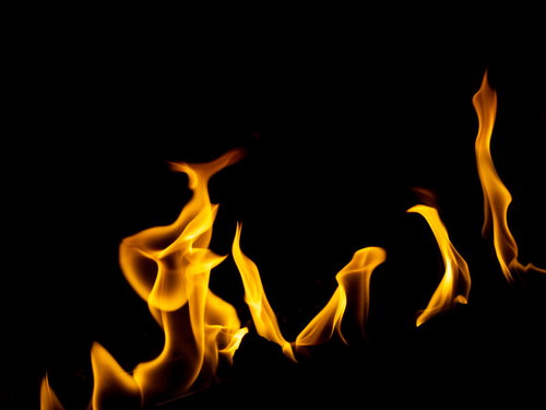 黒い背景に揺れるオレンジ色の炎のメラメラした火の背景