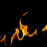 黒背景に立ち上がるオレンジ色の弱めの火炎の写真