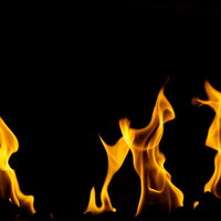 黒背景に激しく燃える鮮やかなオレンジ色の炎の写真