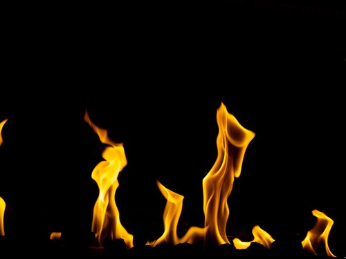 黒背景に立ち上がる火の穂、オレンジと黄色の炎が揺らめく